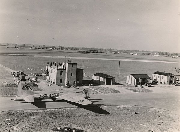 The RAF Molesworth control tower in April 1944.  On the taxiway is a B-17G, tail number 42-97284 "Ain't Misbehavin" - she would fly a total of 48 combat missions during the war.  The "Triangle-C" designator on the verticle stabilizer was the RAF Molesworth designator.  Photograph by Mr. Milton "Chic" Cantor, the photographer of the 303rd BG(H), with thanks to the 303rd "Hell's Angels" historical society.